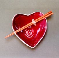 Tazón rojo en forma de corazón con palillos de mad