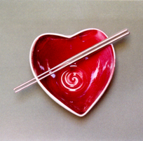 Tazón rojo en forma de corazón con palillos de ace