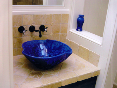 Ein installiertes, kobaltblaues Gefäß-Waschbecken mit symmetrischen Wöbungen.