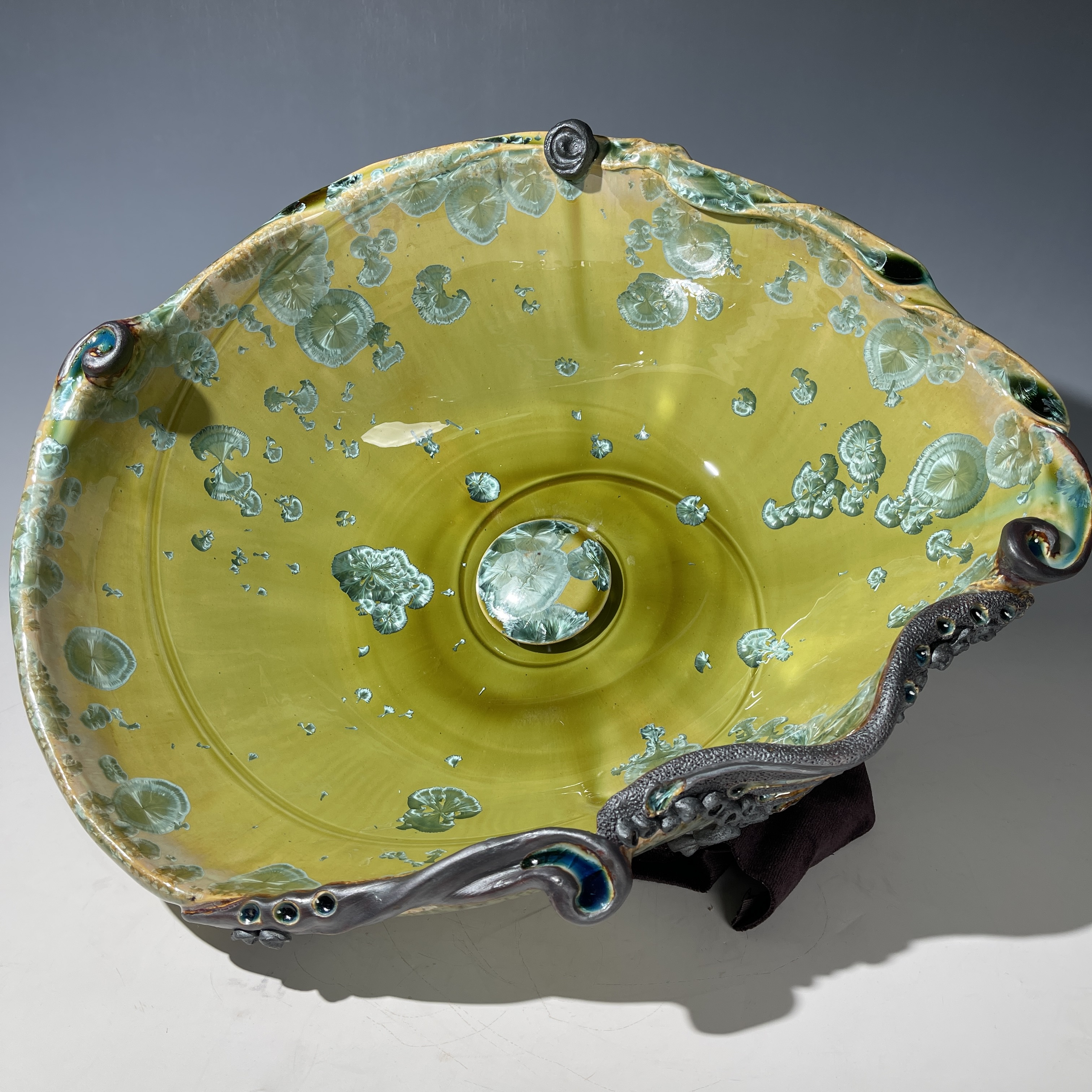 Lavabo con forma ovoide en cristal verde con detalles esculturales arremolinados