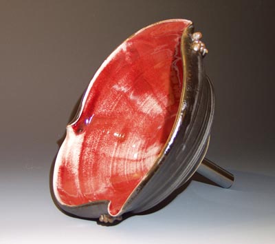 three quarter view symetrical bend custom hand made sink red glaze inside oilspot glaze outside.